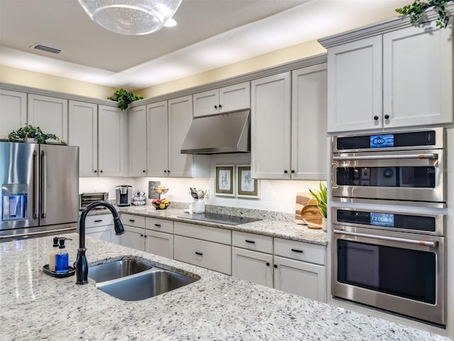 kitchen with stainless steel appliances, sink, gray cabinetry, and light stone countertops