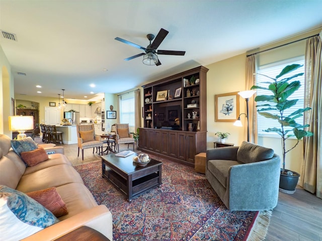 living room featuring ceiling fan, wood-type flooring, and a healthy amount of sunlight