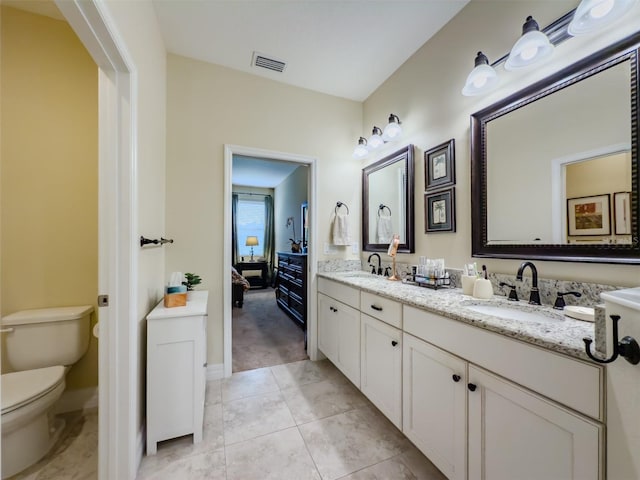 bathroom with toilet, vanity, and tile patterned floors