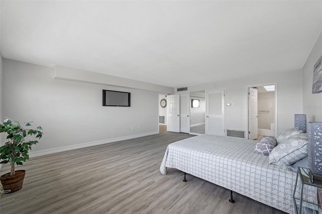 bedroom with connected bathroom and hardwood / wood-style flooring