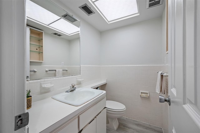 bathroom with tile walls, vanity, hardwood / wood-style flooring, and toilet