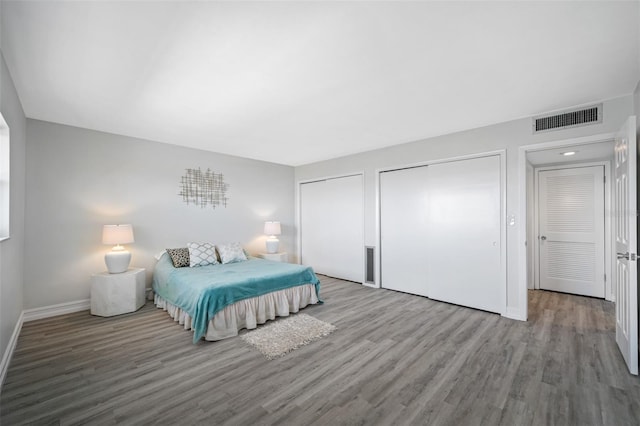 bedroom with light hardwood / wood-style floors and multiple closets