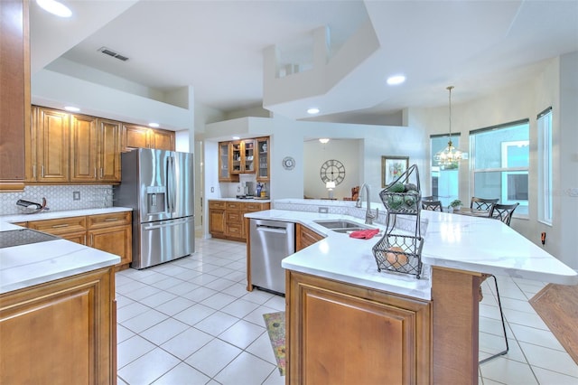 kitchen with tasteful backsplash, a breakfast bar, stainless steel appliances, sink, and hanging light fixtures