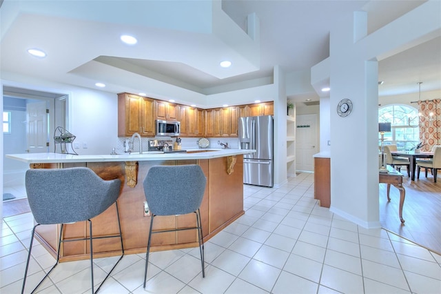 kitchen featuring sink, stainless steel appliances, a raised ceiling, decorative backsplash, and light tile patterned floors