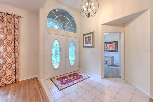 foyer entrance featuring french doors, light tile patterned floors, and a notable chandelier