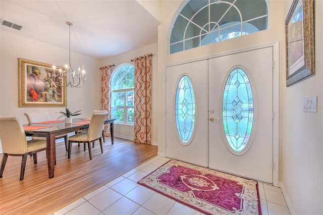 tiled entrance foyer featuring french doors and an inviting chandelier