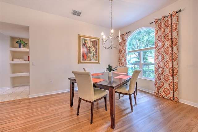 dining space with a chandelier, light hardwood / wood-style floors, and built in features