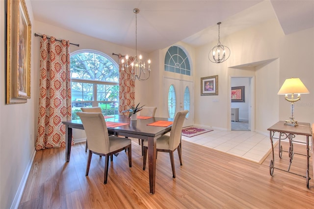 dining space featuring french doors, a chandelier, and light wood-type flooring