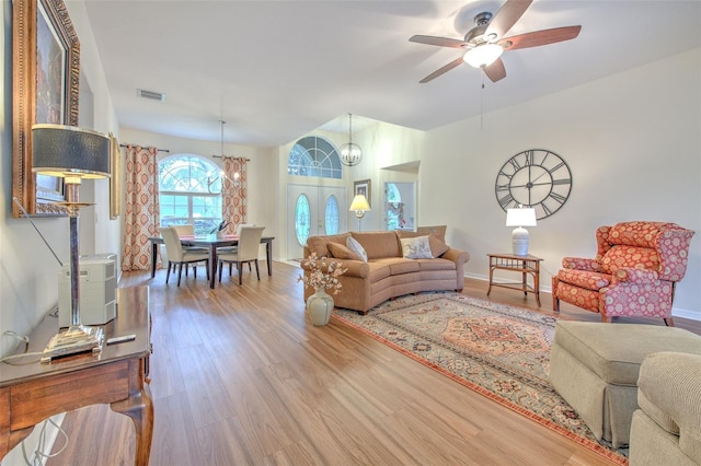 living room featuring french doors, wood-type flooring, and ceiling fan with notable chandelier