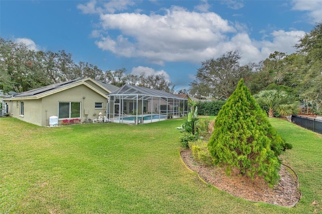 back of property with solar panels, a yard, and a lanai