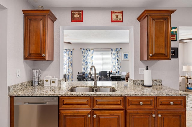 kitchen featuring dishwasher, light stone counters, and sink