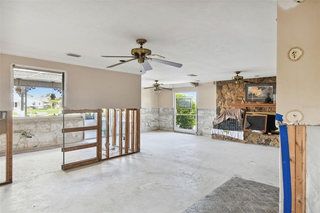 unfurnished living room featuring a stone fireplace, concrete floors, and ceiling fan