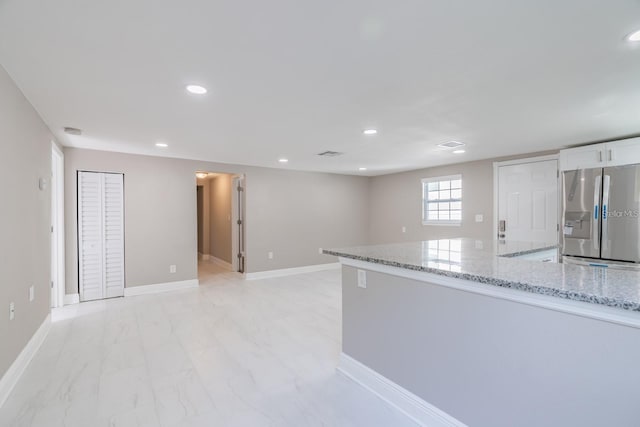 kitchen featuring white cabinetry, light stone countertops, and stainless steel fridge with ice dispenser