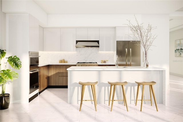 kitchen featuring stainless steel appliances, white cabinets, sink, a kitchen breakfast bar, and wall chimney range hood