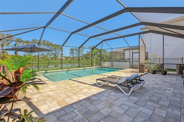 view of pool featuring glass enclosure, a water view, and a patio