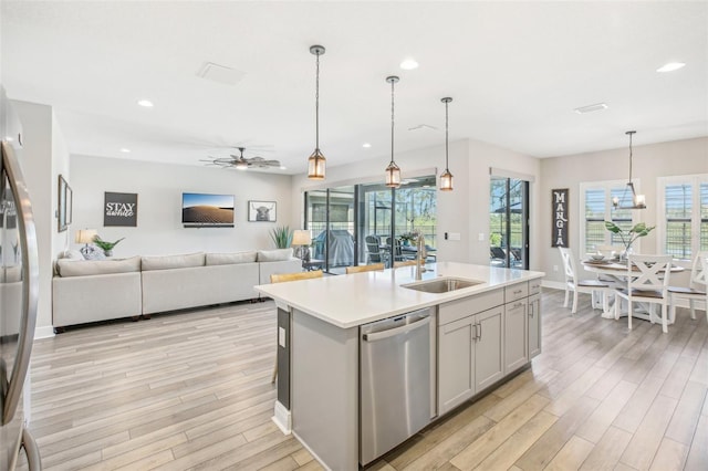 kitchen featuring appliances with stainless steel finishes, decorative light fixtures, sink, a kitchen island with sink, and ceiling fan