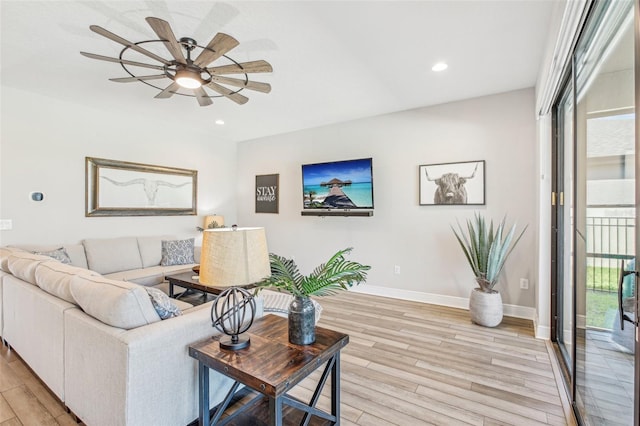 living room with ceiling fan, a wealth of natural light, and light wood-type flooring