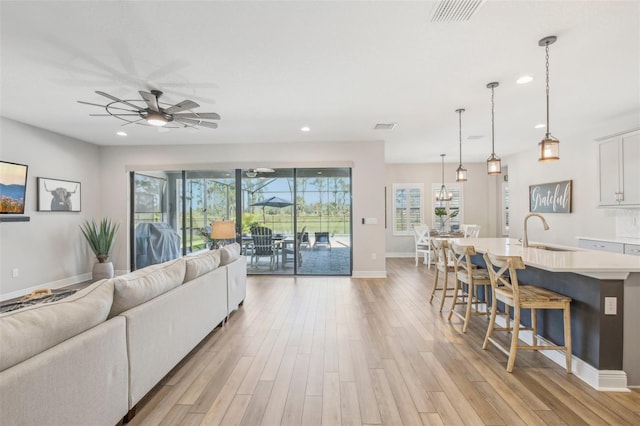 living room featuring ceiling fan, light hardwood / wood-style flooring, and sink