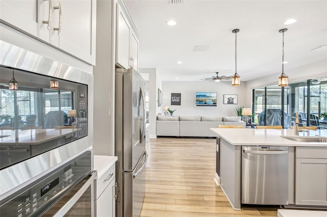 kitchen with pendant lighting, white cabinets, stainless steel appliances, sink, and ceiling fan