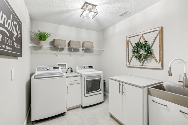 washroom featuring sink, independent washer and dryer, a textured ceiling, and cabinets