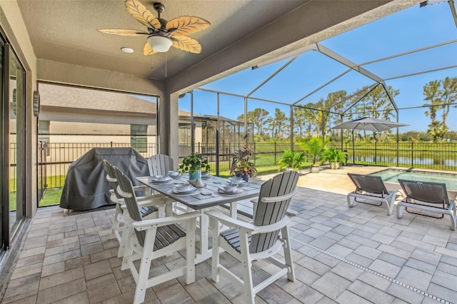 view of patio with a water view, a fenced in pool, ceiling fan, and glass enclosure