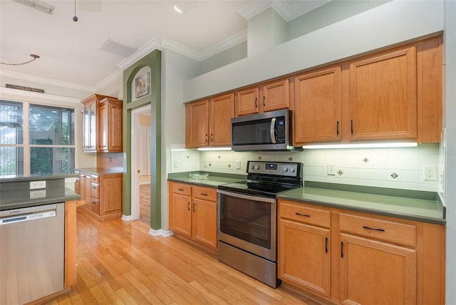 kitchen featuring light wood-type flooring, appliances with stainless steel finishes, decorative backsplash, and crown molding