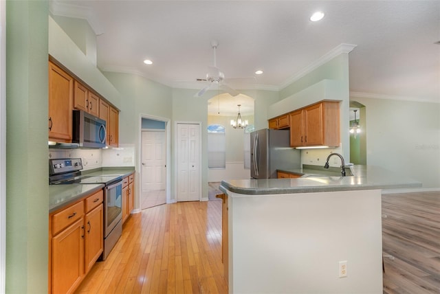 kitchen with stainless steel appliances, kitchen peninsula, sink, crown molding, and light hardwood / wood-style flooring