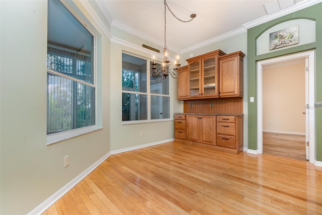 unfurnished dining area with an inviting chandelier, light hardwood / wood-style flooring, and ornamental molding