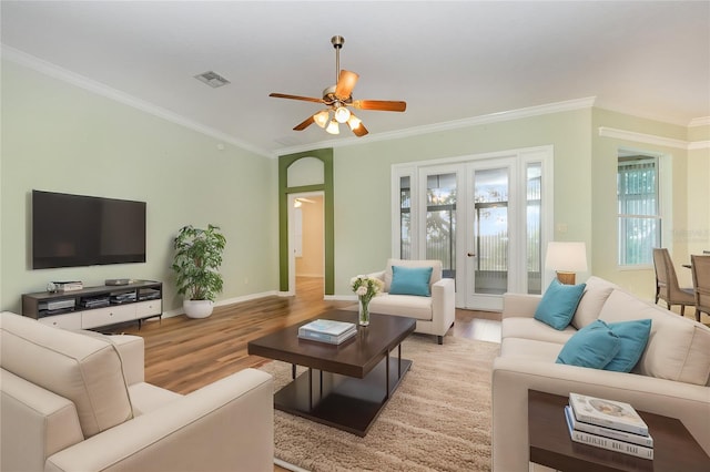 living room featuring french doors, ceiling fan, light wood-type flooring, and crown molding