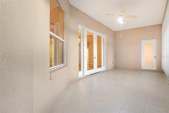 empty room with french doors, light tile patterned floors, and ceiling fan