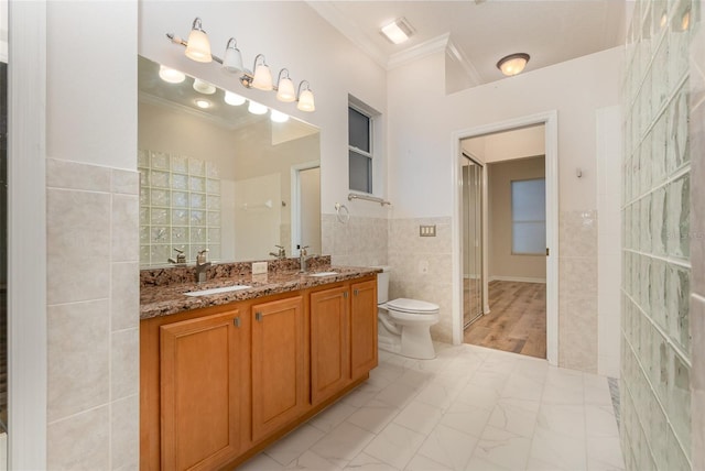 bathroom featuring tile walls, wood-type flooring, crown molding, vanity, and toilet