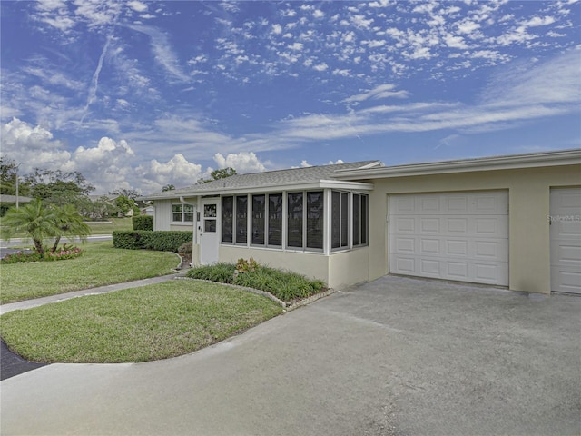 single story home with a garage, a front yard, and a sunroom