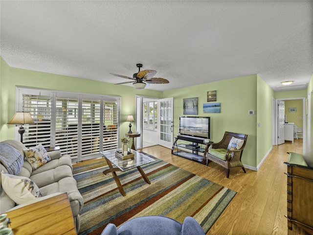 living room featuring ceiling fan, a textured ceiling, and light hardwood / wood-style flooring