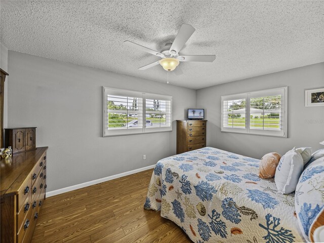 bedroom featuring dark wood-type flooring, ceiling fan, and a textured ceiling