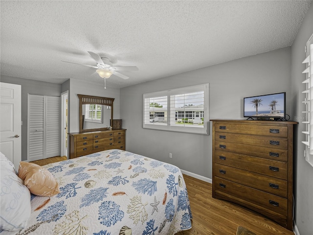 bedroom featuring a closet, hardwood / wood-style floors, ceiling fan, and a textured ceiling