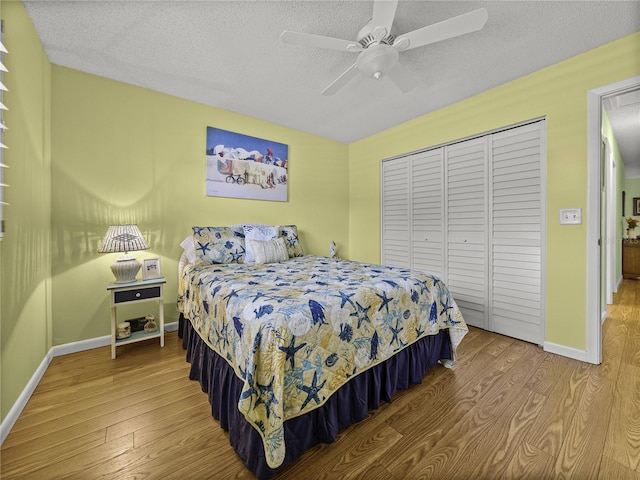 bedroom with ceiling fan, a textured ceiling, a closet, and wood-type flooring