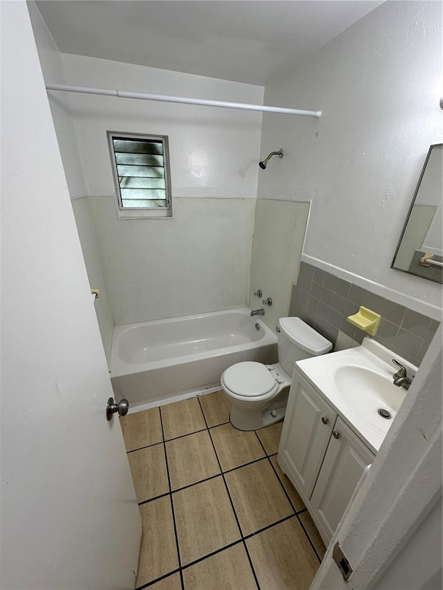 full bathroom with washtub / shower combination, vanity, toilet, and tile walls