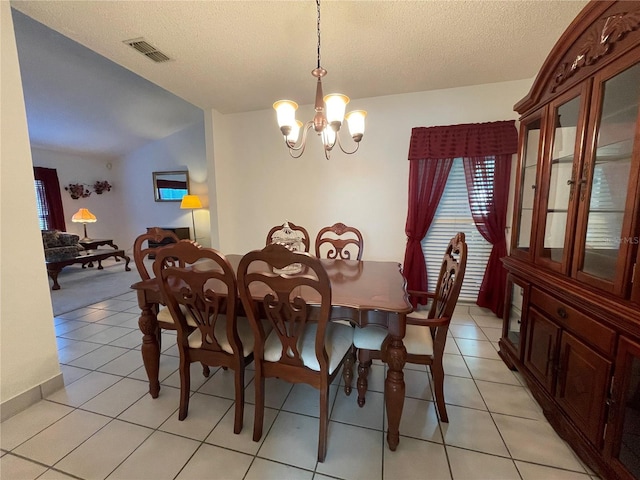 tiled dining area featuring a chandelier and a textured ceiling