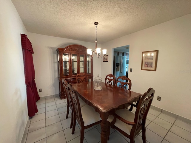 dining area with an inviting chandelier, a textured ceiling, and light tile patterned flooring