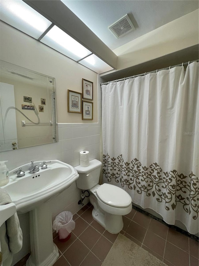 bathroom with toilet, tile walls, a shower with shower curtain, and tile patterned floors