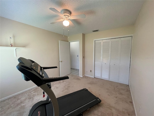 workout area featuring light colored carpet, a textured ceiling, and ceiling fan