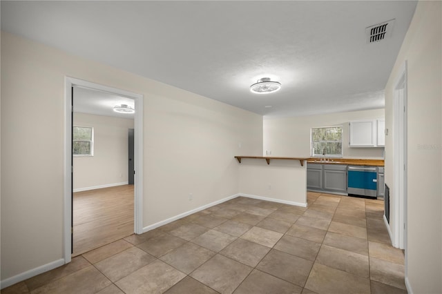 kitchen with kitchen peninsula, white cabinets, a breakfast bar, light hardwood / wood-style flooring, and dishwasher