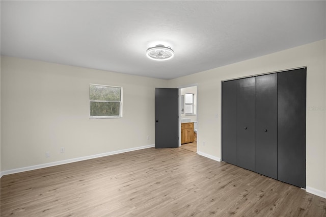 unfurnished bedroom with light hardwood / wood-style flooring, ensuite bathroom, and a closet