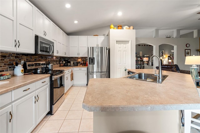 kitchen featuring light tile patterned flooring, stainless steel appliances, white cabinetry, and a kitchen island with sink