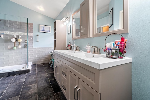 bathroom with lofted ceiling, vanity, and tiled shower