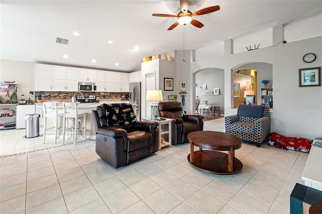 tiled living room featuring ceiling fan and high vaulted ceiling