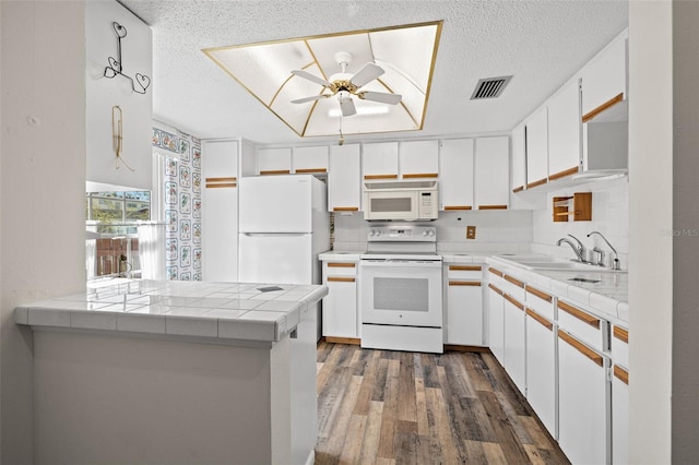 kitchen featuring sink, kitchen peninsula, tile countertops, white appliances, and white cabinets