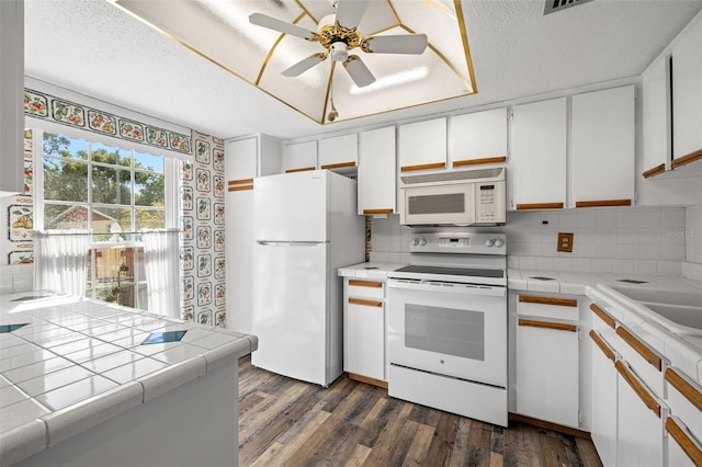 kitchen with tile countertops, white cabinetry, white appliances, and a textured ceiling