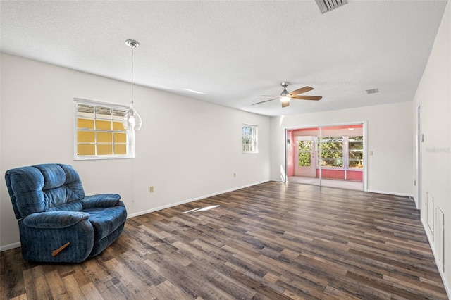 living area with a textured ceiling, ceiling fan, and dark wood-type flooring