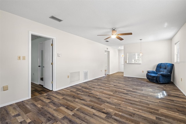 unfurnished living room with ceiling fan, dark hardwood / wood-style flooring, and a textured ceiling